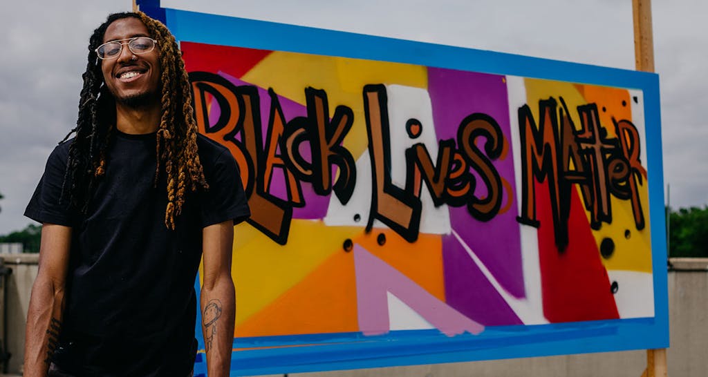 Columbus artist Hakim Callwood in front of his Black Lives Matter mural