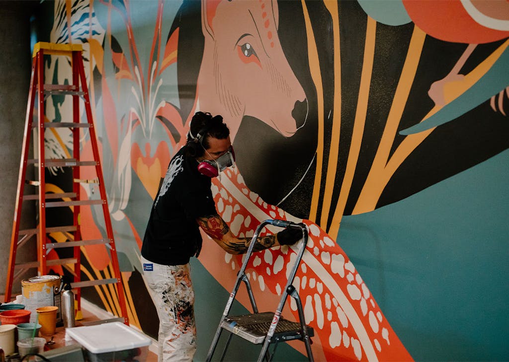A local artist paints a mural inside CoverMyMeds' campus.